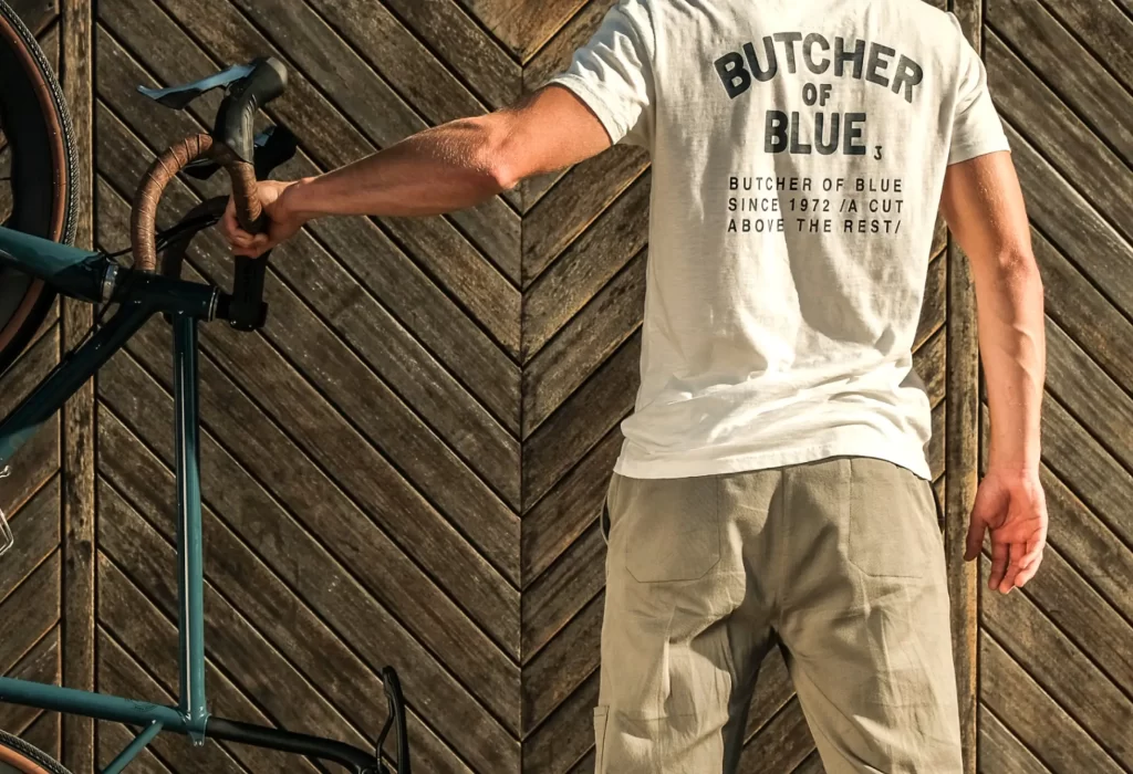 Back of a men with a white Butcher of Blue t-shirt holding a classical blue race bike