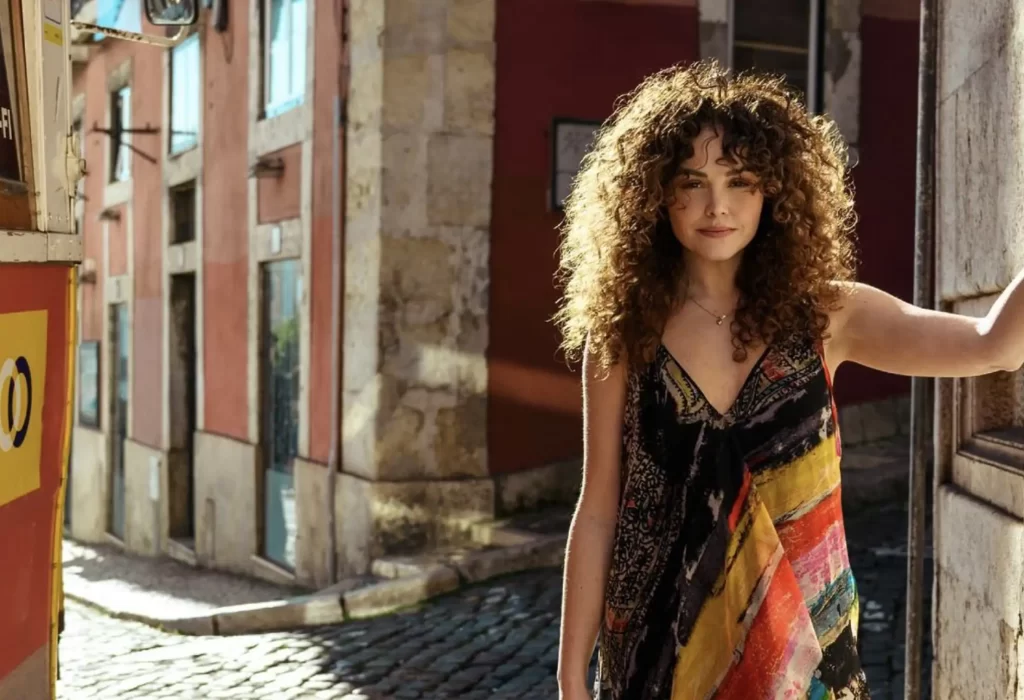 Lady standing in an Italian street showing a Label DOT dress in black, red, and yellow.